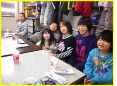 クラブ内の机に並んで座る子ども達